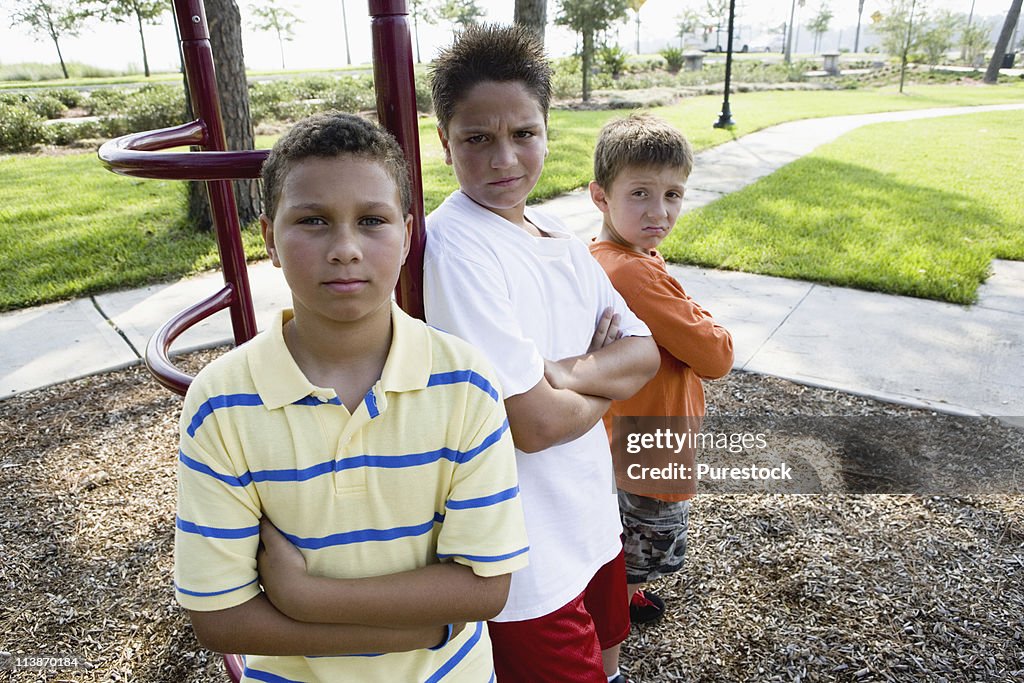 Three boys playfully posing and acting like tough kids at a playground