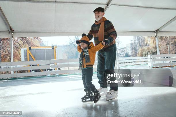 grandfather and grandson on the ice rink, ice skating - family sport winter stock-fotos und bilder