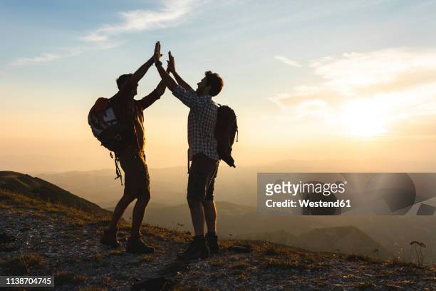 italy, monte nerone, two happy and successful hikers in the mountains at sunset - mates celebrating stock pictures, royalty-free photos & images