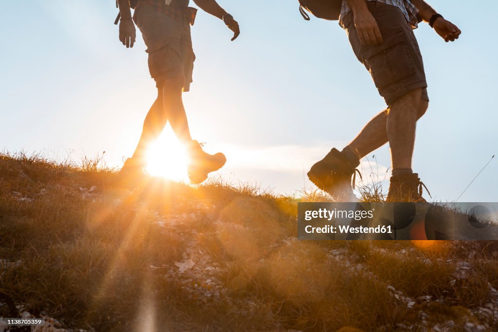 Italy, Monte Nerone, close-up of two men hiking in mountains at sunset