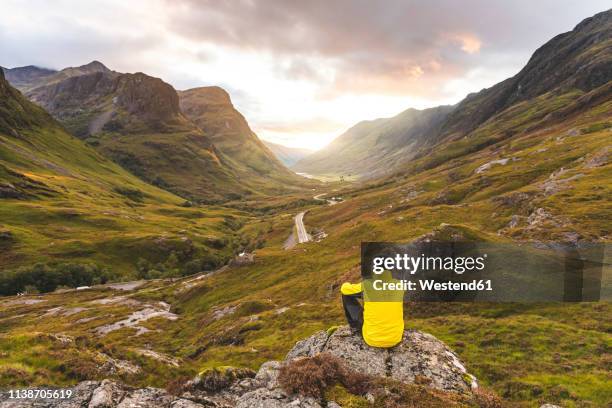 uk, scotland, man looking at view with the three sisters of glencoe mountains on the left and the a82 road in the middle of the valley - glencoe schotland stockfoto's en -beelden