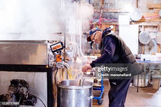 senior mannen werken bij sugar shack voor ahornsiroop familie-industrie - sugar shack stockfoto's en -beelden