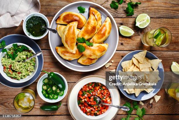 traditional mexican food - meat empanadas with cilantro chimichurri sauce, guacamole, salsa, tortilla chips and mojito - empanada stock-fotos und bilder