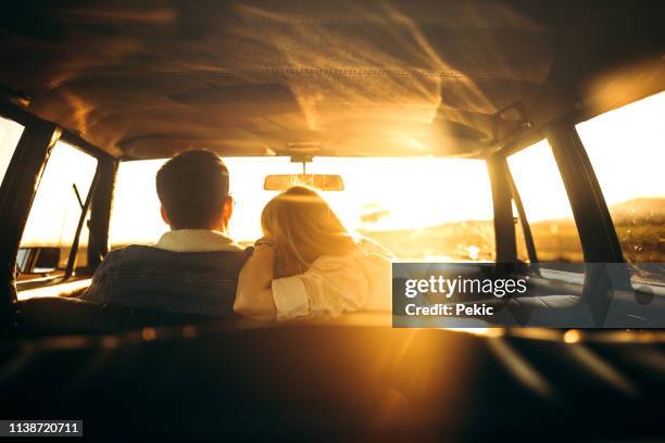 rear view of couple in car - embracing car stock pictures, royalty-free photos & images