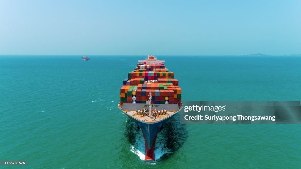 Aerial front view Container Ship full load container going to seaport or unload at container warehouse on the blue sea. Logistics, import export, shipping or transportation.