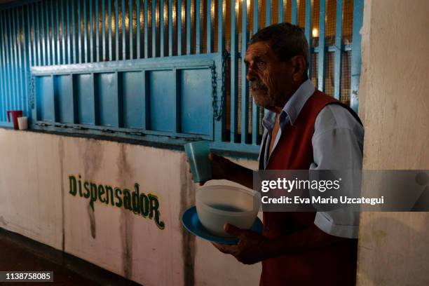 Man holds a plastic container and a cup as he waits for the soup that will be served for lunch at the nursery home "Casa Hogar Madre Teresa de...