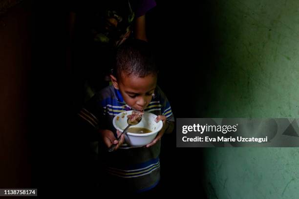 Boy of Barrio Unión Sector Las Casitas eat soup prepared and donated by Alto Restaurant in the house of a neighbor at Petare on April 12, 2019 in...