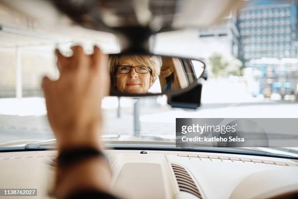 sie ist sicher, dass sie während der fahrt eine klare vision rund um sich hat - vehicle mirror stock-fotos und bilder