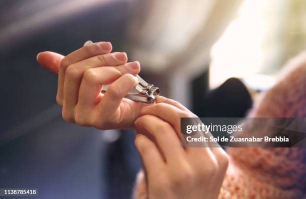 young woman taking care of her nails - doorknippen stockfoto's en -beelden