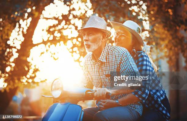 pareja senior en una bicicleta de scooter conduciendo por las calles de la ciudad. - holiday scooter fotografías e imágenes de stock