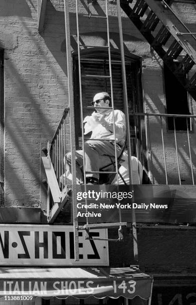 Making of movie The Godfather on Mott Street in Manhattan. Movie watcher sits on fire escape eating his lunch and watches making of the film.