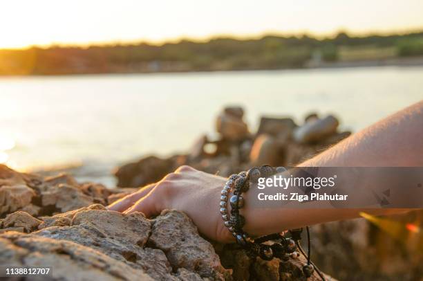 hand with bracelets by the seaside - bralets stock pictures, royalty-free photos & images