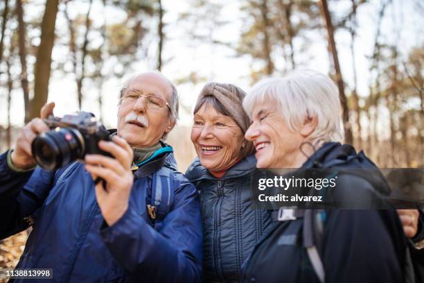 senior hikers looking at their pictures on camera - senior photographer stock pictures, royalty-free photos & images