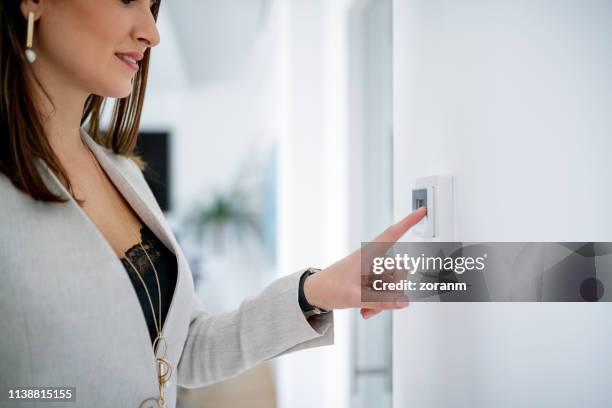 woman with finger on lights switch - turn off light stock pictures, royalty-free photos & images