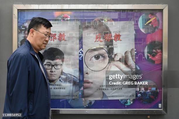 Man walks past anti-cult posters beside a sidewalk in Beijing on April 23, 2019. - The posters have gone up in Beijing as it approaches the 20th...