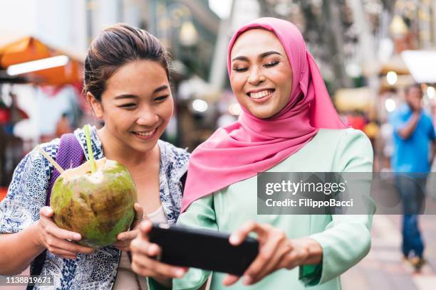 two friends having selfie together at the market - coconut water stock pictures, royalty-free photos & images