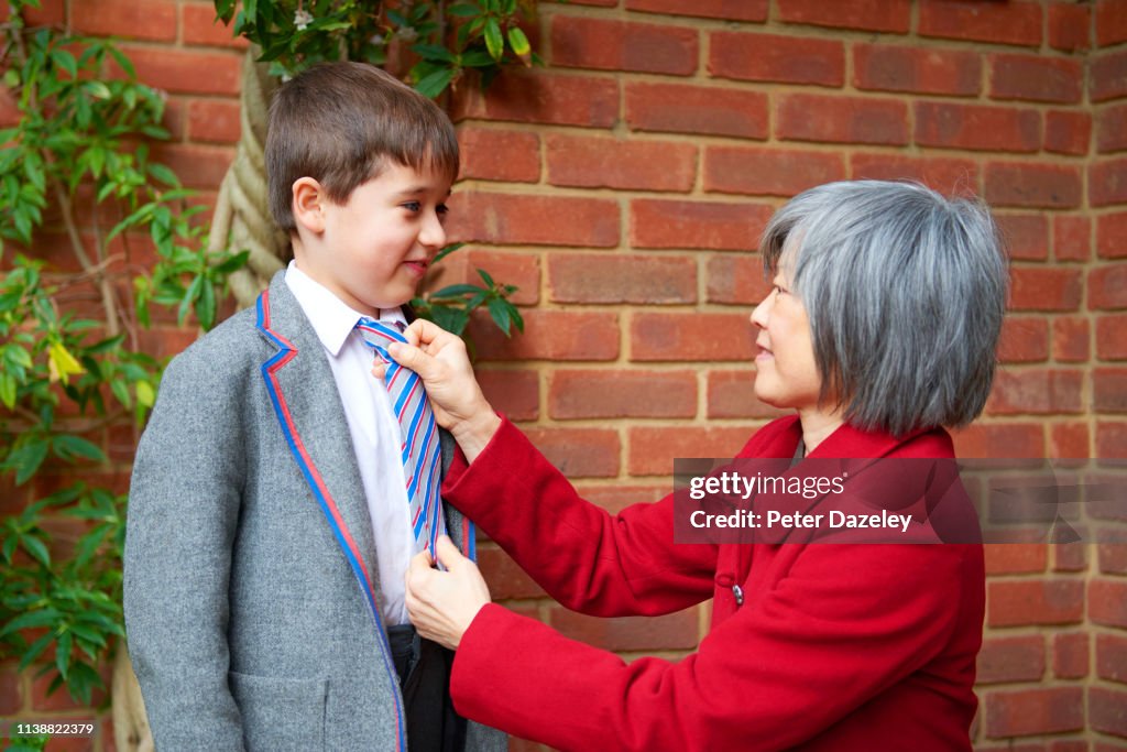 Tiger mother doing up schoolboy son's tie