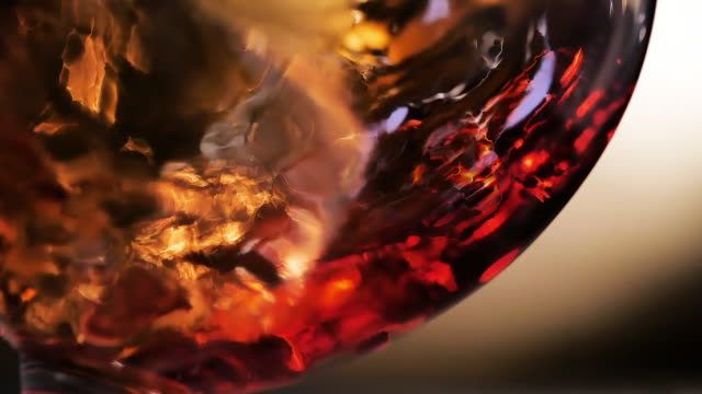 Cognac is rotated in a glass. On dark background.