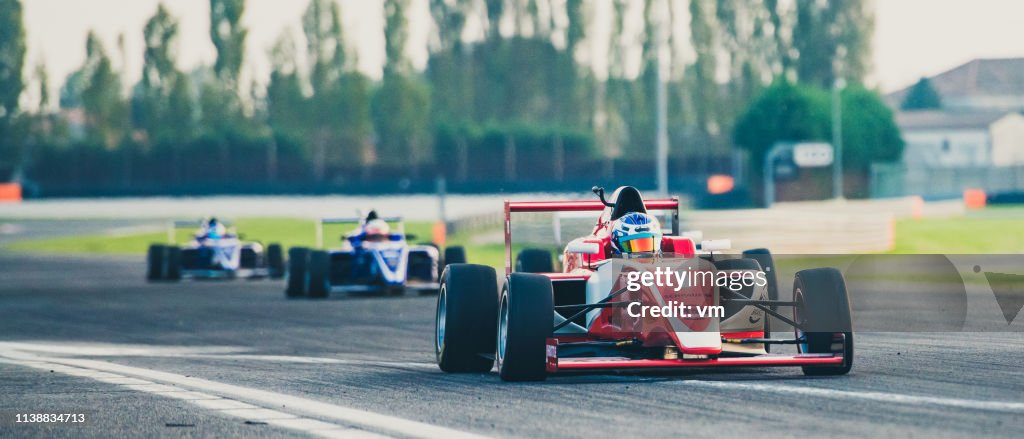 Trois voitures de course de formule sur la piste de course