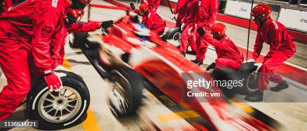 red formula race car leaving the pit stop - grand prix motor racing stock pictures, royalty-free photos & images