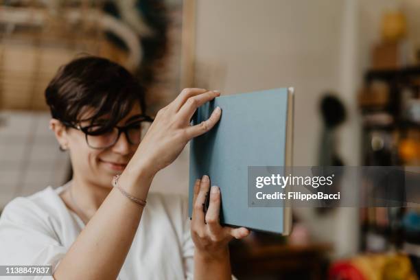 jeune femme adulte regardant la reliure d'un cahier - reliures photos et images de collection