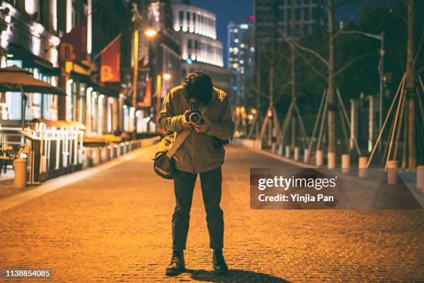 young man using a film camera at night - chinese people posing for camera stockfoto's en -beelden