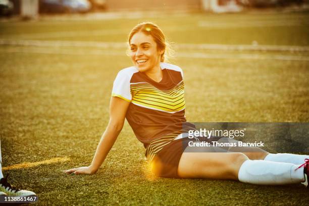 Smiling female soccer player sitting on field after game