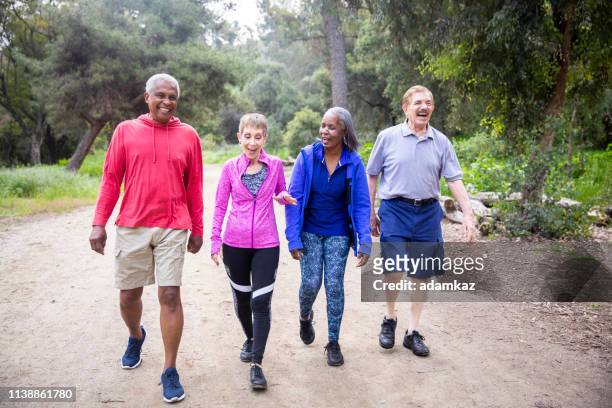 amici anziani che camminano sul sentiero della foresta - seniors and group and diverse foto e immagini stock