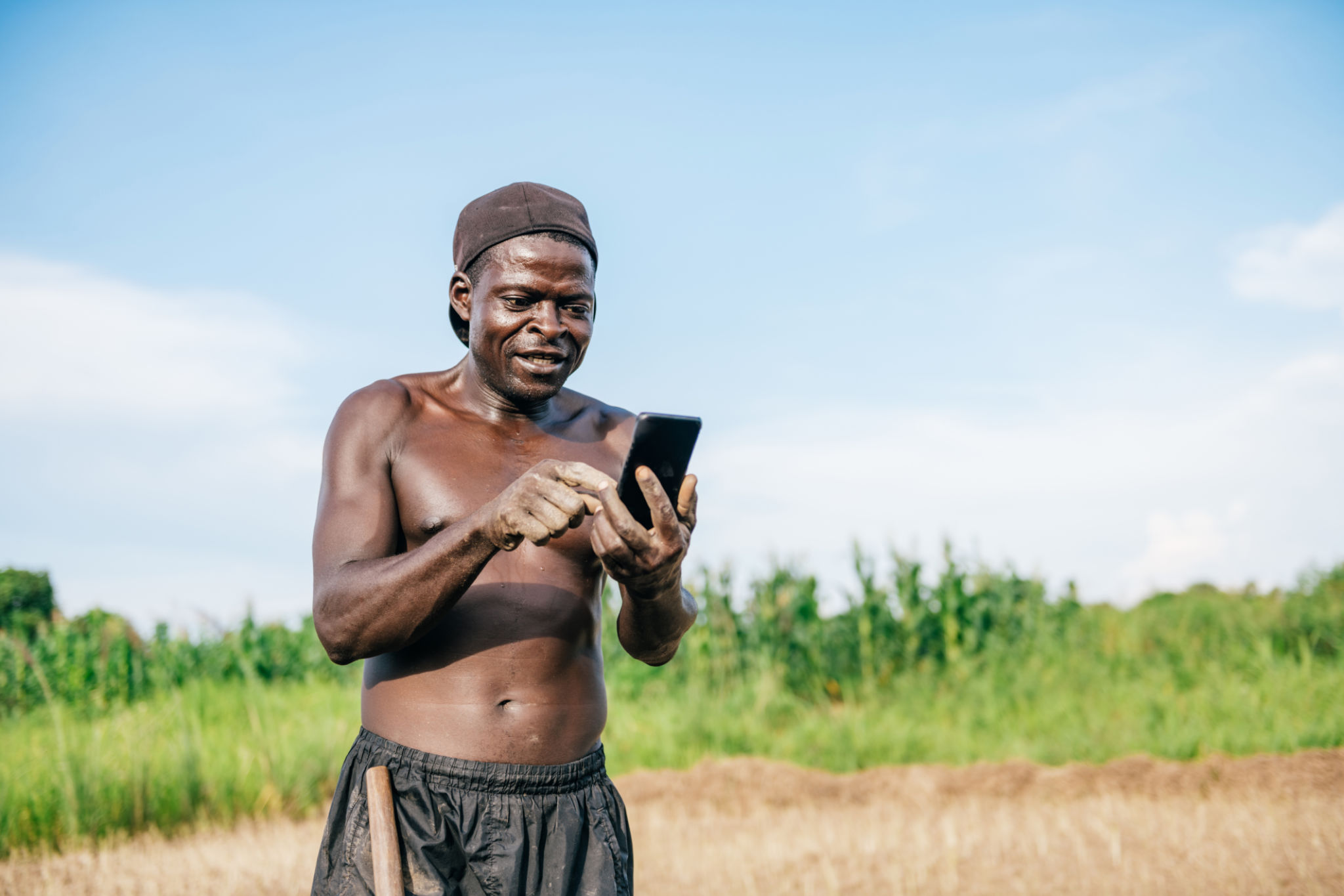 agriculteur africain regardant sur le mobile sur le terrain agriculteur africain regardant sur le mobile sur le terrain