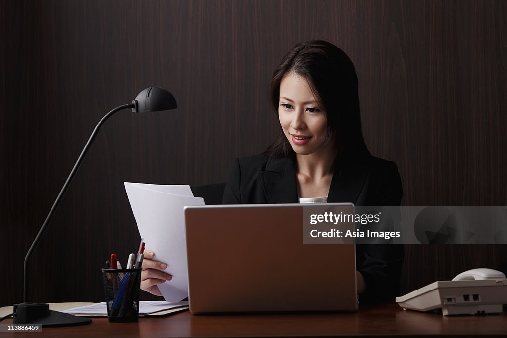 Chinese woman sitting at desk looking at papers