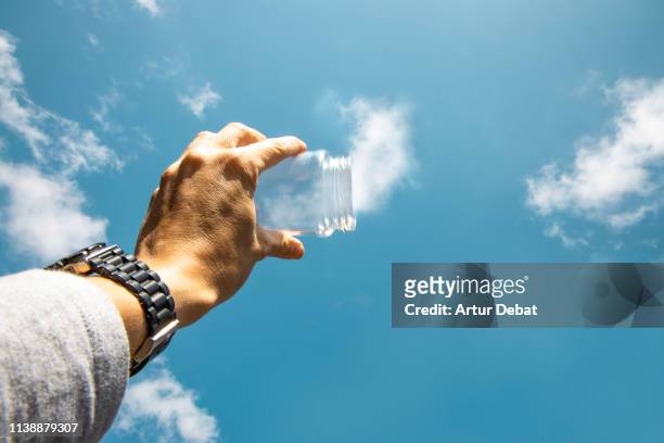 capturing the clouds from the sky with with glass pot in creative picture from personal perspective. - clear sky photos et images de collection
