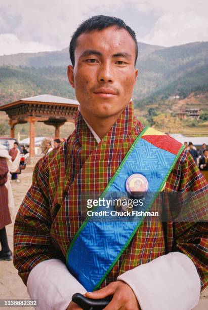 Bhutanese man outside Khuruthang Lhakhang wearing buttons with pictures of King Jigme Singye Wangchuck, Punakha, Bhutan, 2004.