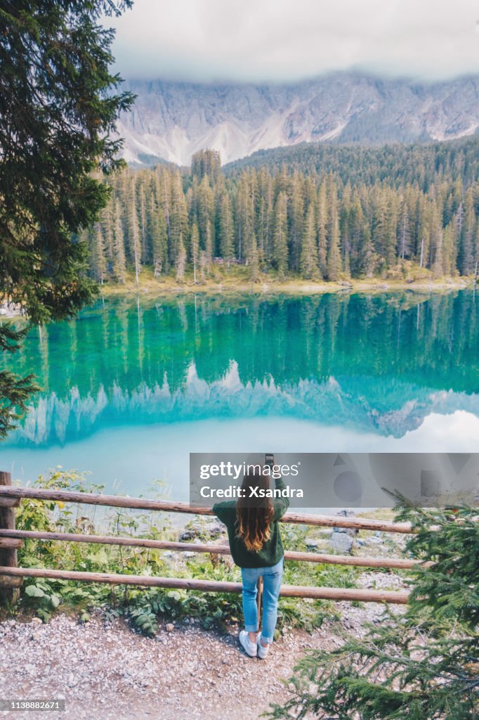 Young woman taking photo at Carezza lake in Italy