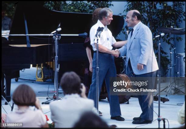 American politician US President Jimmy Carter shakes hands with Jazz promoter George Wein onstage during a White House Jazz concert, on the South...