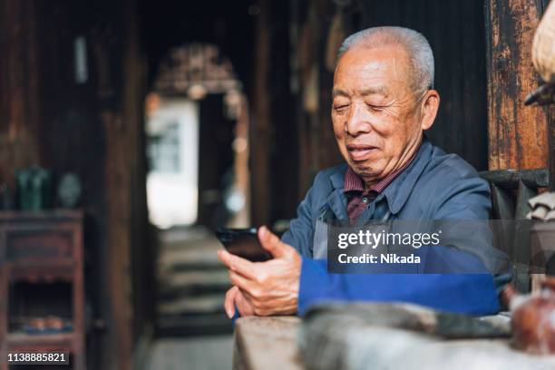 chinese senior man using mobile phone - elderly chinese man stock pictures, royalty-free photos & images