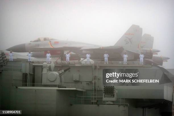 Sailors stand near fighter jets on the deck of the Chinese People's Liberation Army Navy aircraft carrier Liaoning as it participates in a naval...