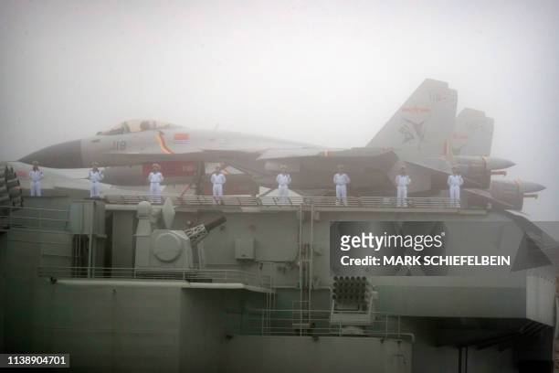 Sailors stand near fighter jets on the deck of the Chinese People's Liberation Army Navy aircraft carrier Liaoning as it participates in a naval...
