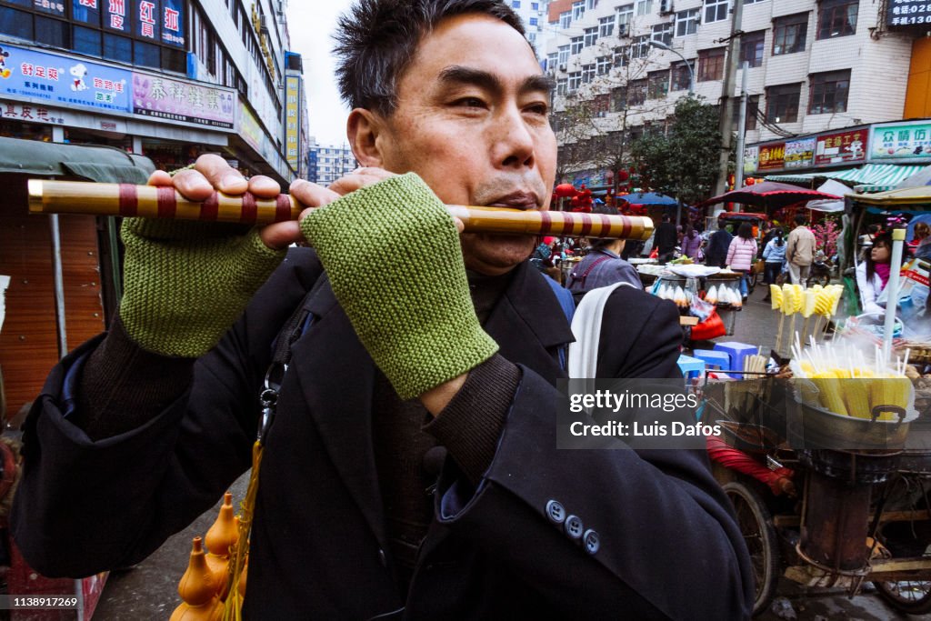 Busker playing a bamboo flute in Chengdu