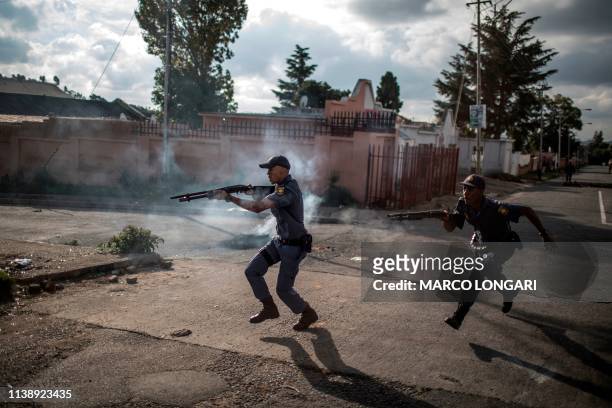 South African police officers fire rubber bullet as they chase protestors in the streets of Johannesburg, on April 23, 2019 during a protest against...