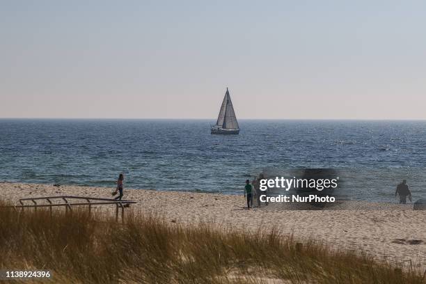 People walking on the Baltic sea sandy beach in city of Hel during sunny spring weather are seen in Sopot, Poland on 22 April 2019