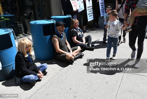Tourist walk past PETA supporters outside the Millennium Times Square New York in midtown Manhattan April 23 chained to plastic barrels similar to...