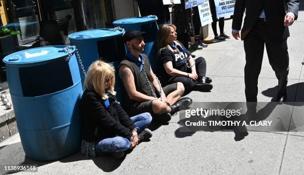 People walk past PETA supporters outside the Millennium Times Square New York in midtown Manhattan April 23 chained to plastic barrels similar to...