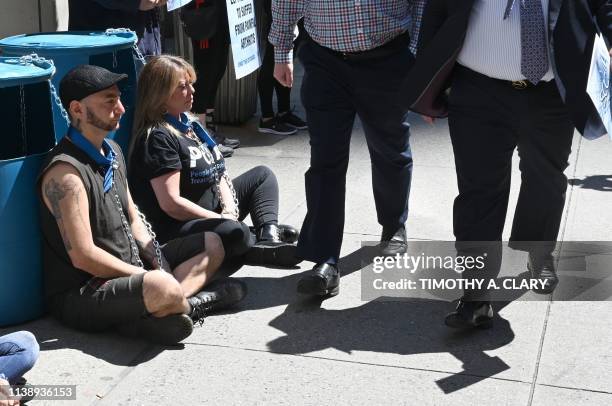 People walk past PETA supporters outside the Millennium Times Square New York in midtown Manhattan April 23 chained to plastic barrels similar to...