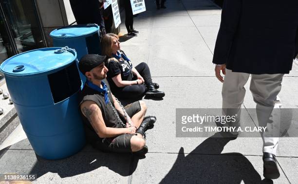 People walk past PETA supporters outside the Millennium Times Square New York in midtown Manhattan April 23 chained to plastic barrels similar to...