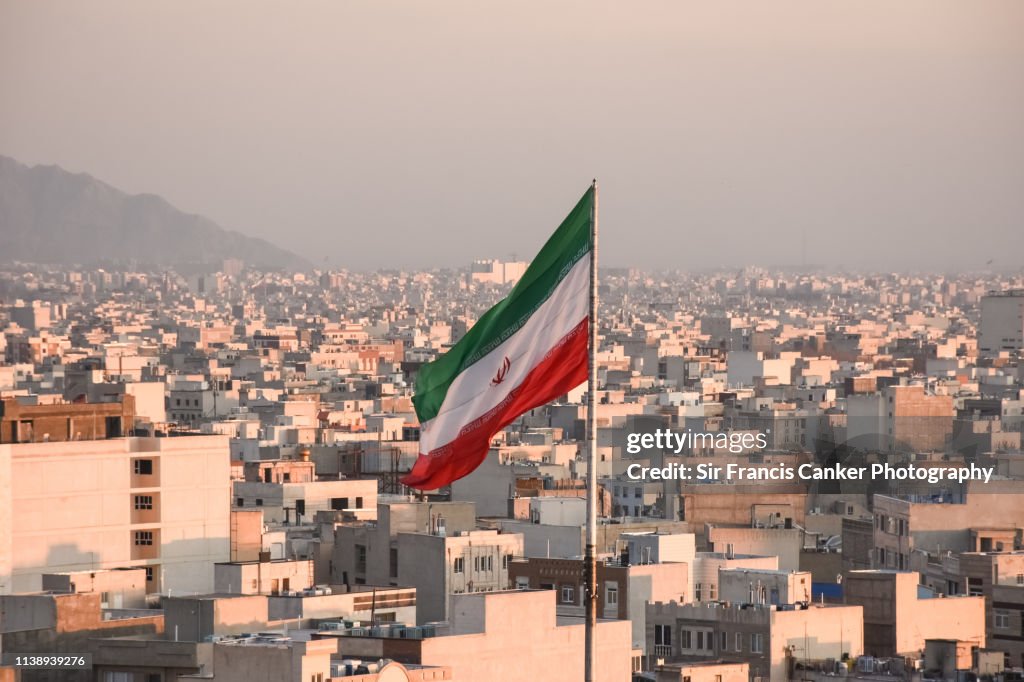 Iranian flag waving with city skyline on background in Tehran, Iran