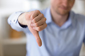 Dissatisfied business man showing thumbs down at workplace