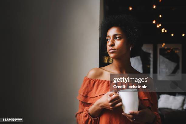 porträt einer jungen frau, die in ihrer wohnung in downtown los angeles kaffee kaffee serviert - schwache beleuchtung stock-fotos und bilder