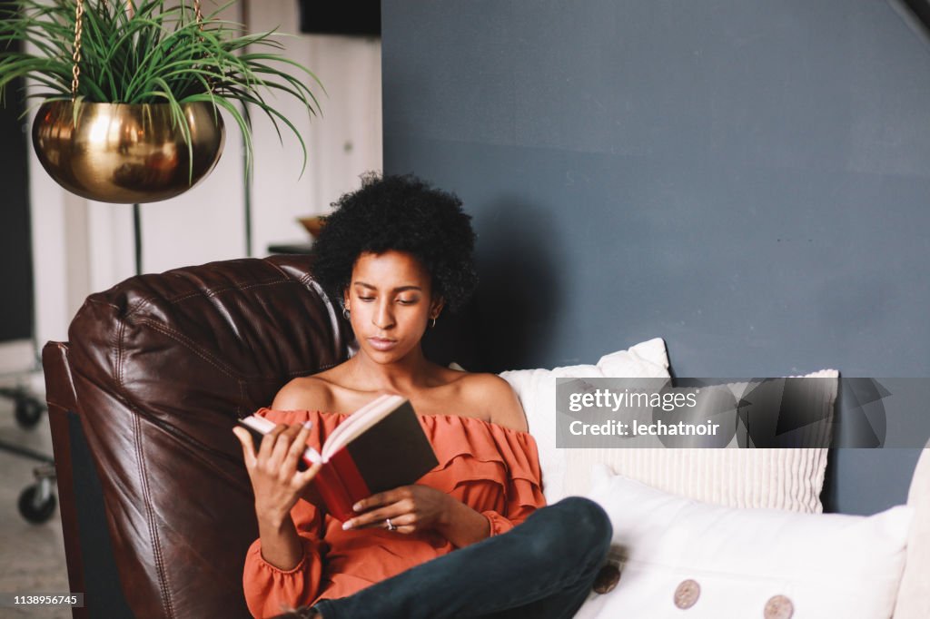 Portrait of a young woman relaxing and reading in her Downtown Los Angeles apartment