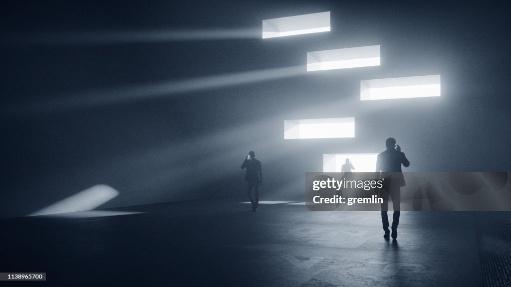 Men on the phone walking in dark, futuristic street