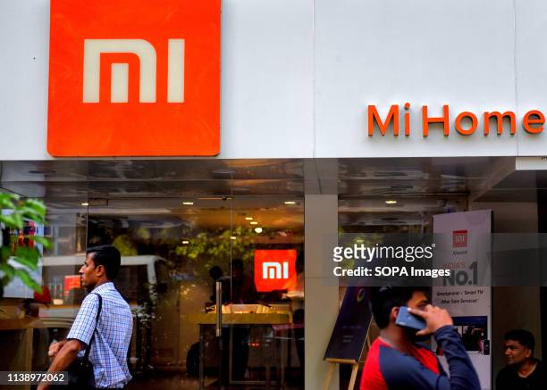 People are seen walking past an MI home mobile store in Kolkata.